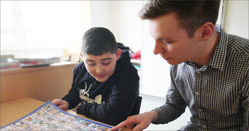 Erzieher in Ausbildung schaut mit einem Schüler ein Bilderbuch an